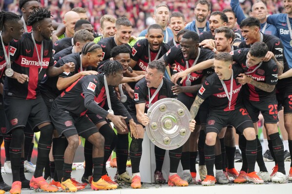 Granit Xhaka của Leverkusen, ở giữa, ăn mừng với chiếc cúp khi đội của anh ấy giành chiến thắng trong trận bóng đá Bundesliga Đức giữa Bayer Leverkusen và FC Augsburg tại BayArena ở Leverkusen, Đức, Thứ Bảy, ngày 18 tháng 5 năm 2024. Bayer Leverkusen đã lần đầu tiên giành được chức vô địch Bundesliga thời gian.  Đây là đội đầu tiên trong lịch sử Bundesliga giành chức vô địch bất bại cả mùa giải.  (Ảnh AP/Martin Meissner)